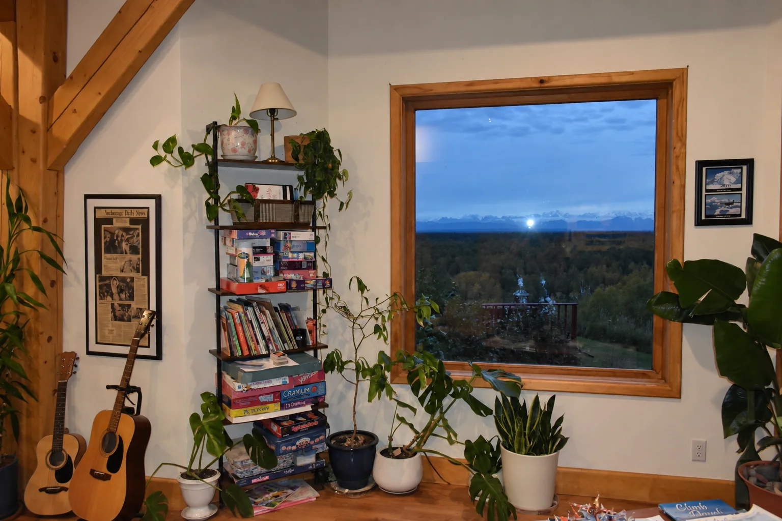 Reading and music corner with guitars, books, board games and a window over the treetops at Denali Overlook Inn