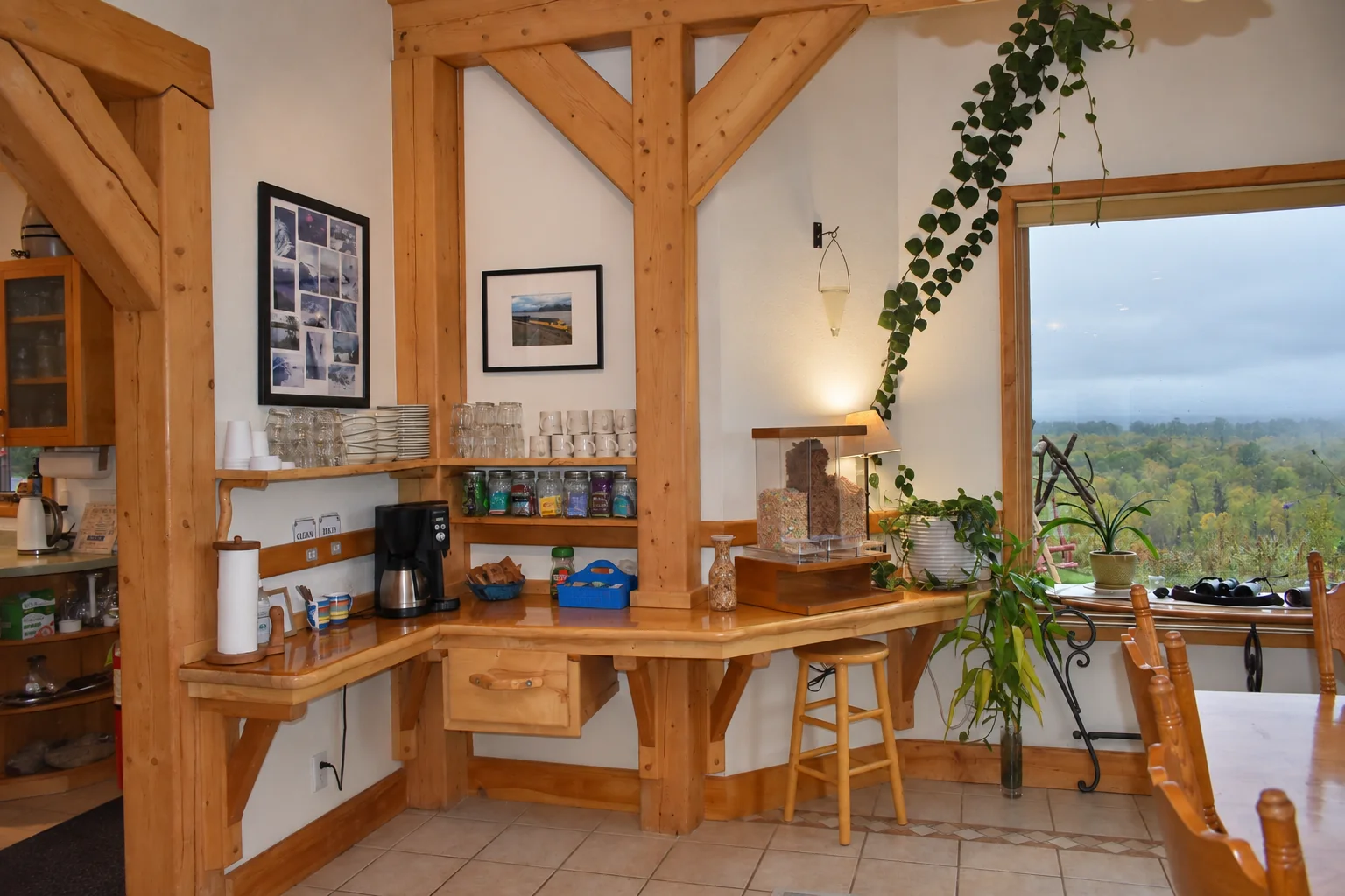 Coffee and tea station with mugs, glasses and a coffee maker beside a window at Denali Overlook Inn