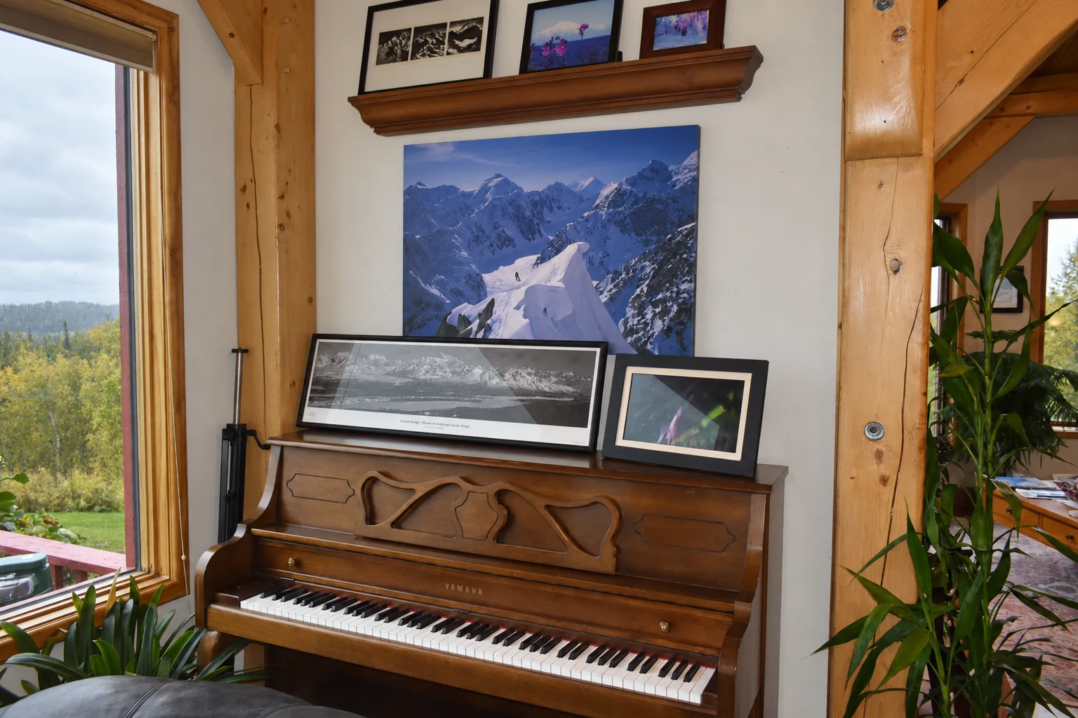 Upright piano with framed Alaska photographs in the shared common area at Denali Overlook Inn