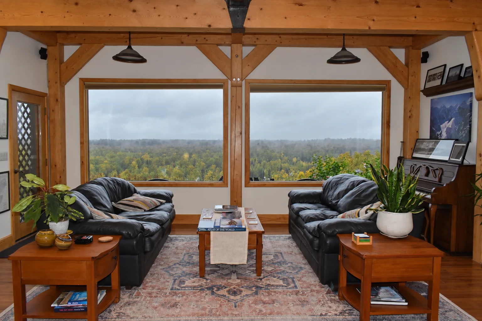 Shared lounge with leather sofas facing large windows over the surrounding forest at Denali Overlook Inn